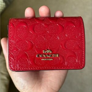 Brand new vibrant red coach wallet. Comes with a gold chain and two charms